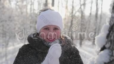 女孩走在冬天的<strong>树林</strong>里，扔雪，微笑，笑。 在新鲜空气中<strong>游</strong>走。